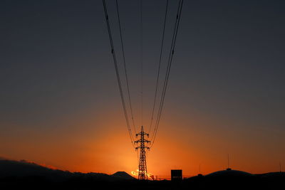 Silhouette of electricity pylon against sky during sunset