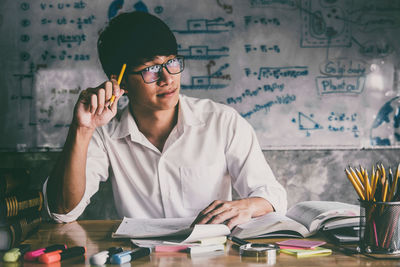 Portrait of young man reading book on table