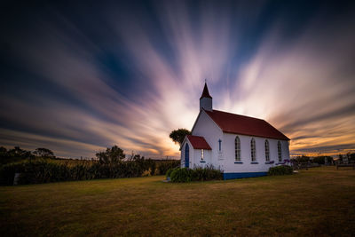 Church in field against sky during sunset. long exposure