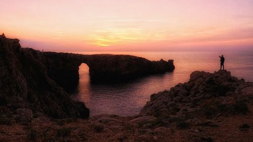 Rock formations by sea against sky during sunset