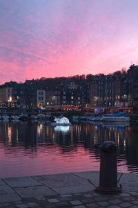 Illuminated cityscape against sky at sunset