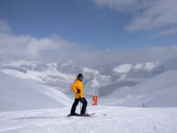 Man standing on snowcapped mountain against sky