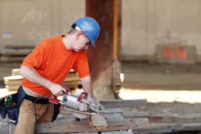 Male construction worker making wood cut