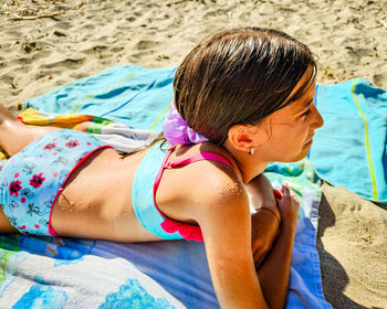 Side view of young woman sitting at beach