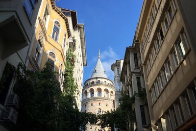 Low angle view of galata tower amidst buildings on sunny day