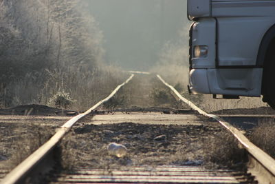 Cropped image of vehicle by railroad track in morning