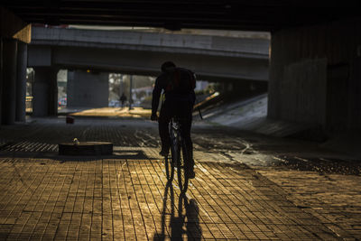 Rear view of man cycling on footpath