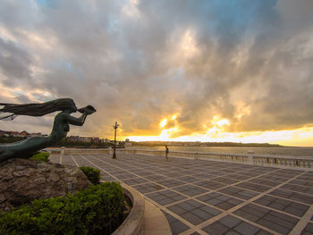Statue of mermaid by the sea with beautiful big clouds at sunset. taken in santander, spain.