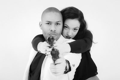 Portrait of man and woman holding gun against white background