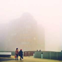 Full length rear view of woman standing in foggy weather