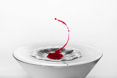 Close-up of water splashing in glass against white background