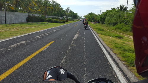 Cropped image of man riding motorcycle on road