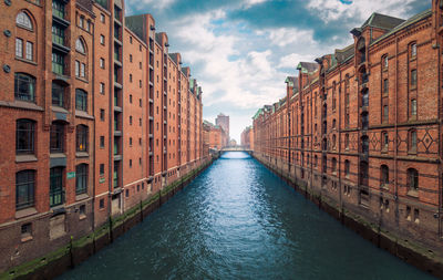 Canal amidst city against sky