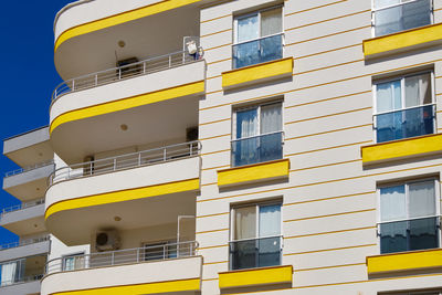 Balconies and windows of yellow color decorated multi storey residential building. modern apartment