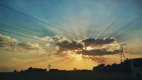 Low angle view of silhouette electricity pylon against sky during sunset