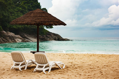 Chair on beach by sea against sky