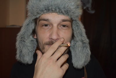 Portrait of man wearing fur hat while smoking cigarette