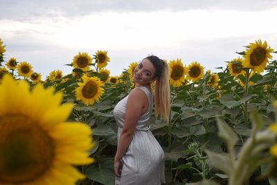 Portrait of smiling young woman standing on field against sky