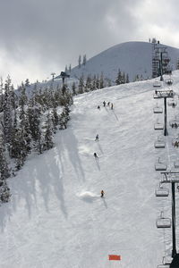 People skiing on snowcapped mountain against sky