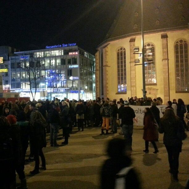 large group of people, men, architecture, built structure, city, building exterior, person, illuminated, lifestyles, city life, street, walking, crowd, night, leisure activity, road, building, city street, outdoors