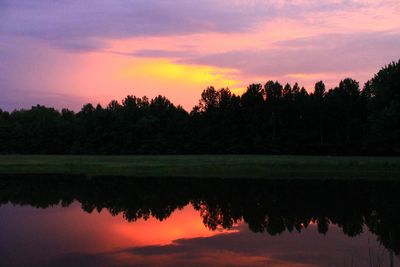 Reflection of silhouette trees in lake against sky during sunset