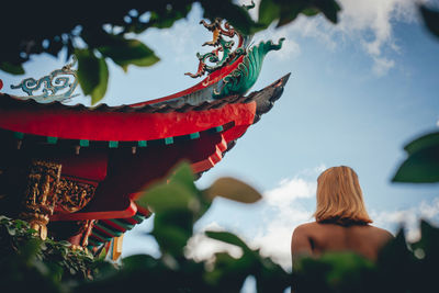 Woman by temple against sky