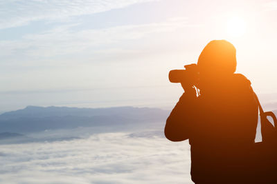 Man photographing against sky during sunset