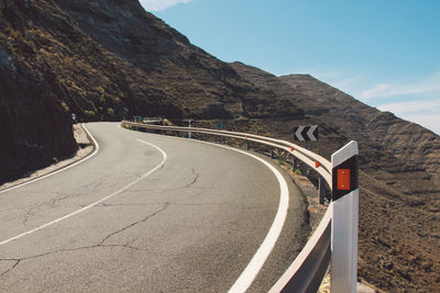 Road leading towards mountains against sky