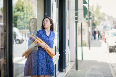 Young woman buying a french baguette