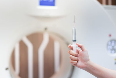 Cropped hand of doctor holding syringe at hospital