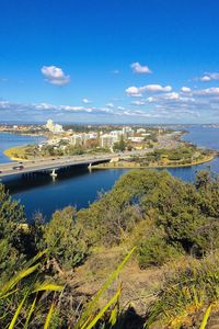 Aerial view of city by sea against blue sky