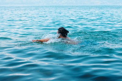 Rear view of shirtless man swimming in sea