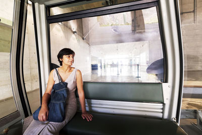 Woman wearing shoulder bag looking away while sitting in cable car