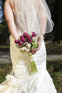 Midsection of bride holding bouquet