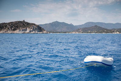 Scenic view of sea by mountain against sky