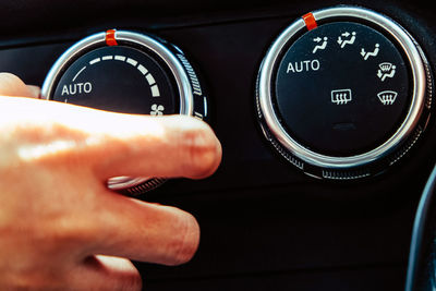 Cropped hand of man adjusting knob in car