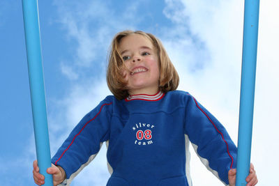 Low angle view of cheerful girl playing with jungle gym against sky