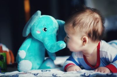 Cute baby boy with toy lying on bed at home