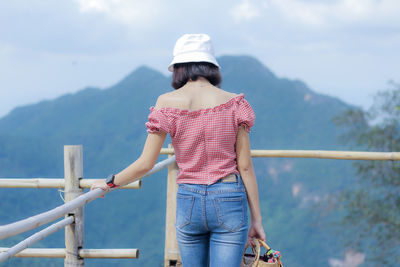 Woman standing on railing against mountain