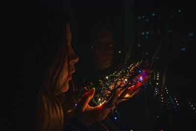 Close-up of woman with illuminated lighting equipment in darkroom