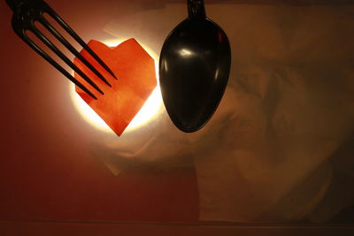 Close-up of illuminated pendant light on table against wall