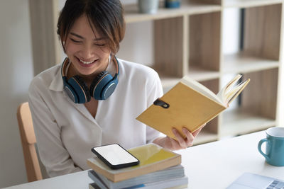 Portrait of a smiling young woman reading book