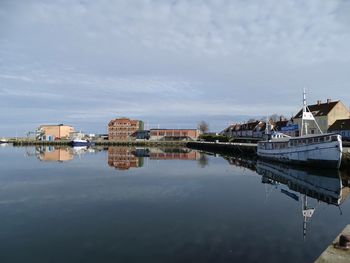 Buildings by river against sky in city