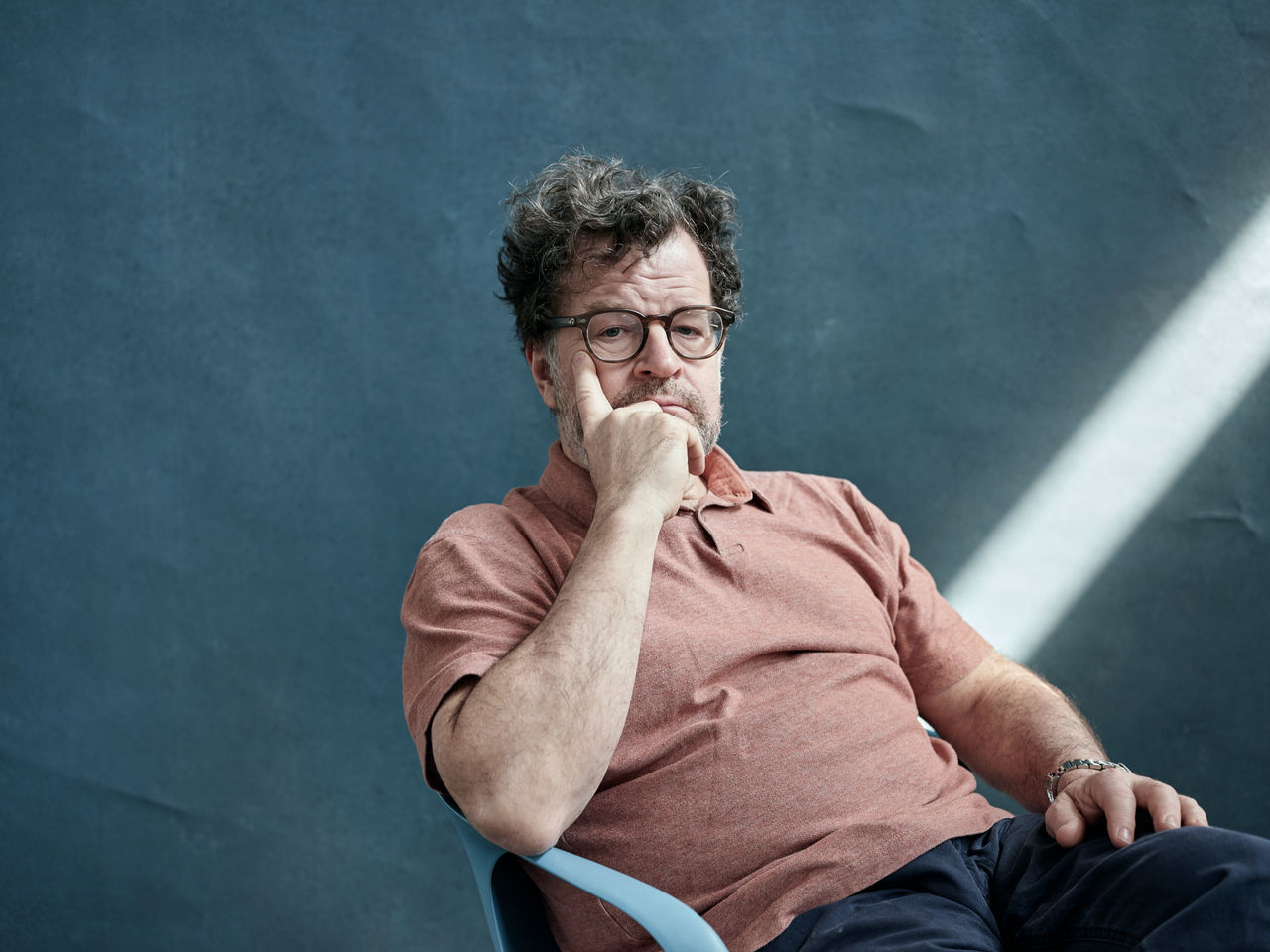 one person, sitting, eyeglasses, men, glasses, portrait, front view, males, real people, adult, casual clothing, three quarter length, contemplation, indoors, studio shot, mature adult, looking at camera, looking, hand