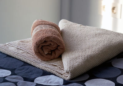 Close-up of rolled up towel on bed at home
