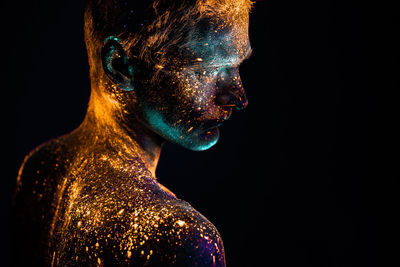 Close-up of shirtless male model with powder paint against black background