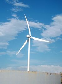 Low angle view of wind turbines on land against sky