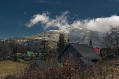 Houses on field by buildings against sky