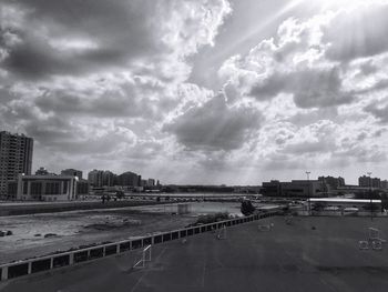 Road by buildings in city against sky