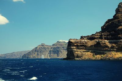 Rock formations by sea against blue sky